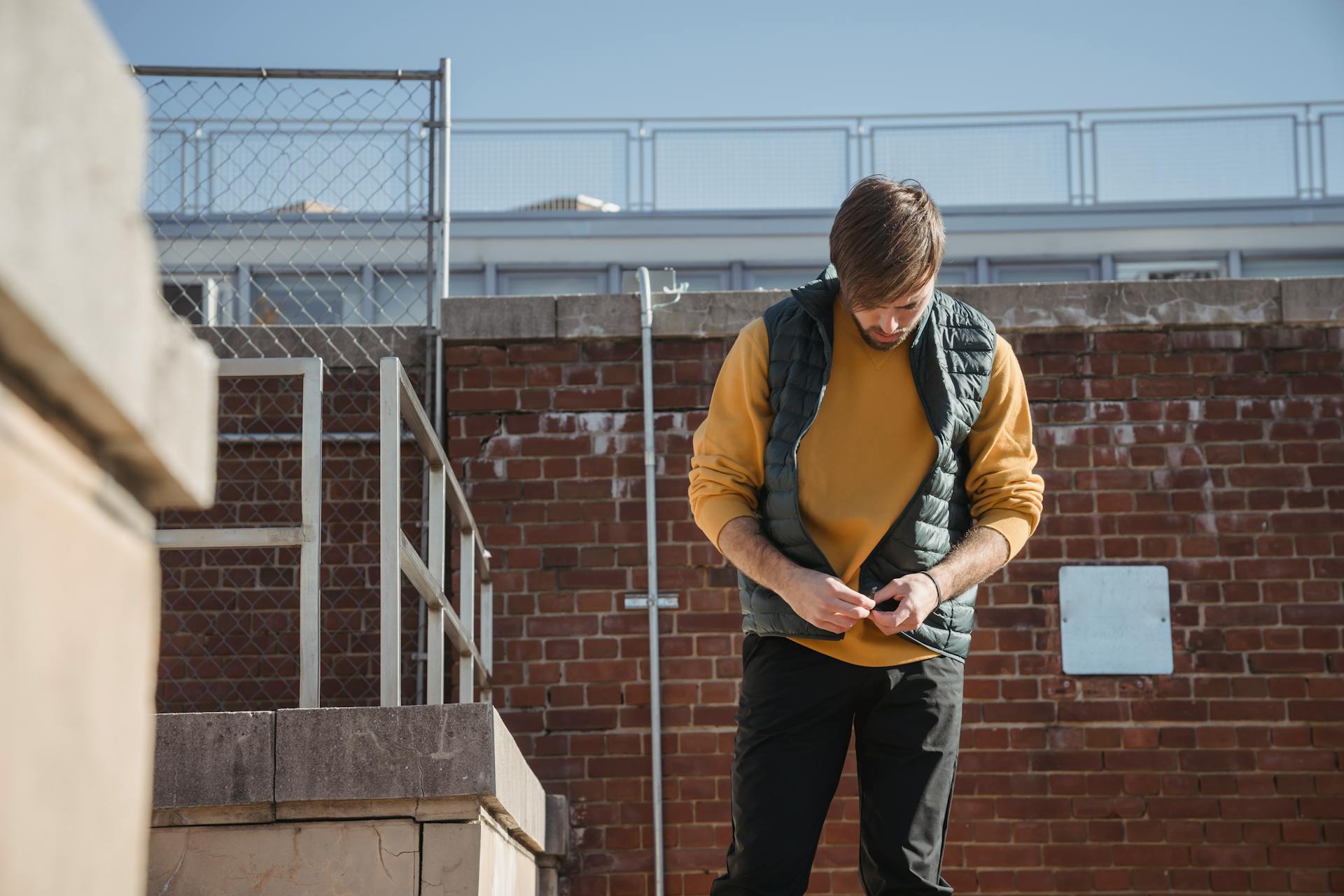 Concentrated man zipping waistcoat on roof