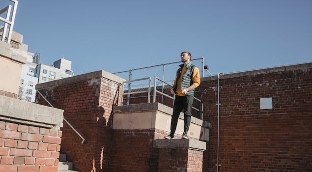 Man standing thoughtfully on an urban brick staircase in a city landscape.