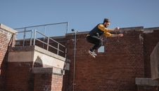 Active man jumping off brick building