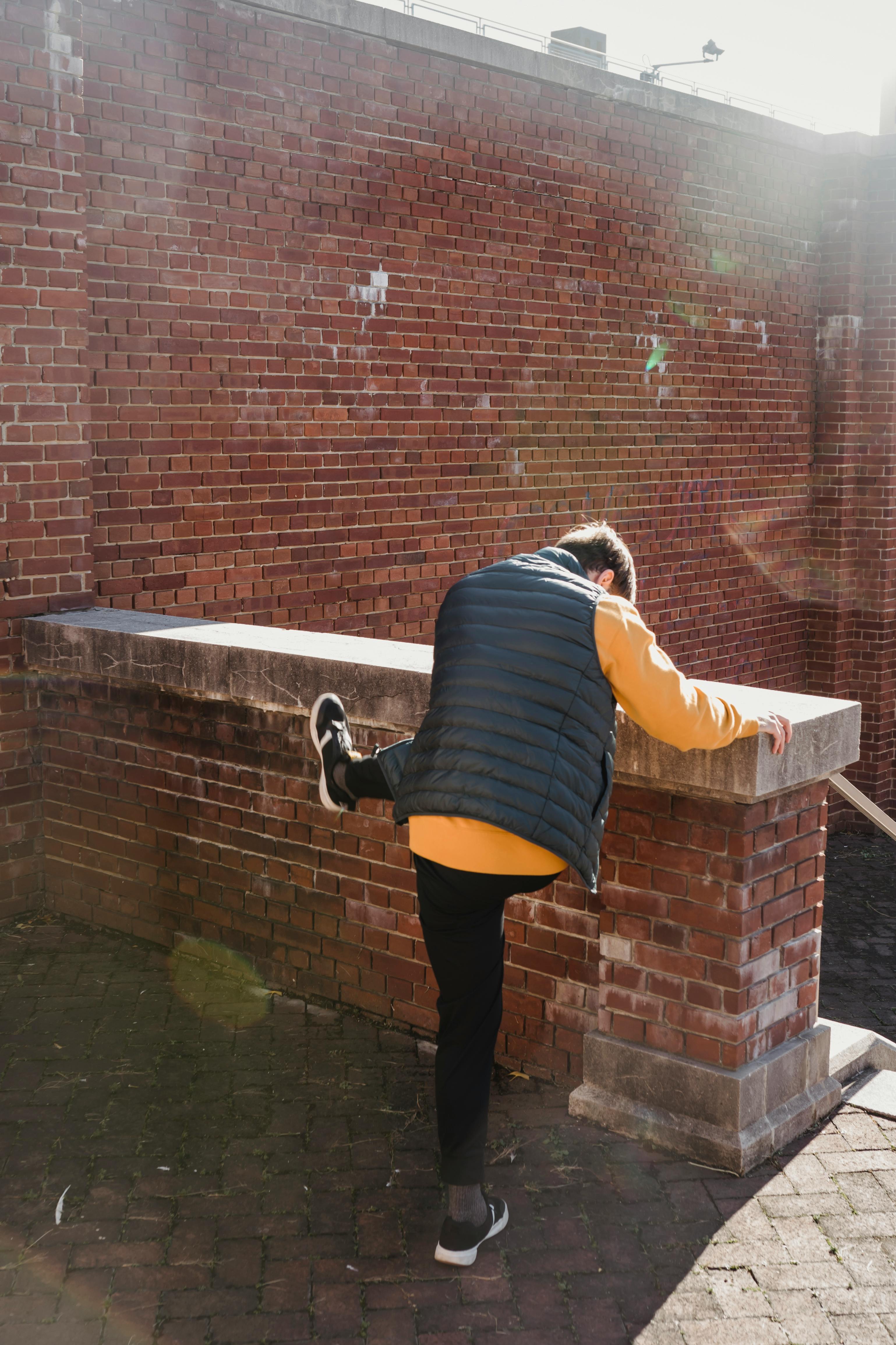 anonymous man jumping over brick border