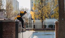 Active sportsman jumping over high fence