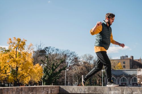 Free Side view of happy sportsman in sportswear performing extreme run on roof in sunny autumn Stock Photo