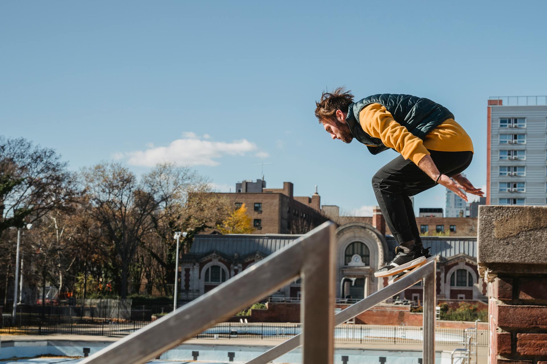 Full body of focused male athlete in sneakers practicing parkour stunts on urban building