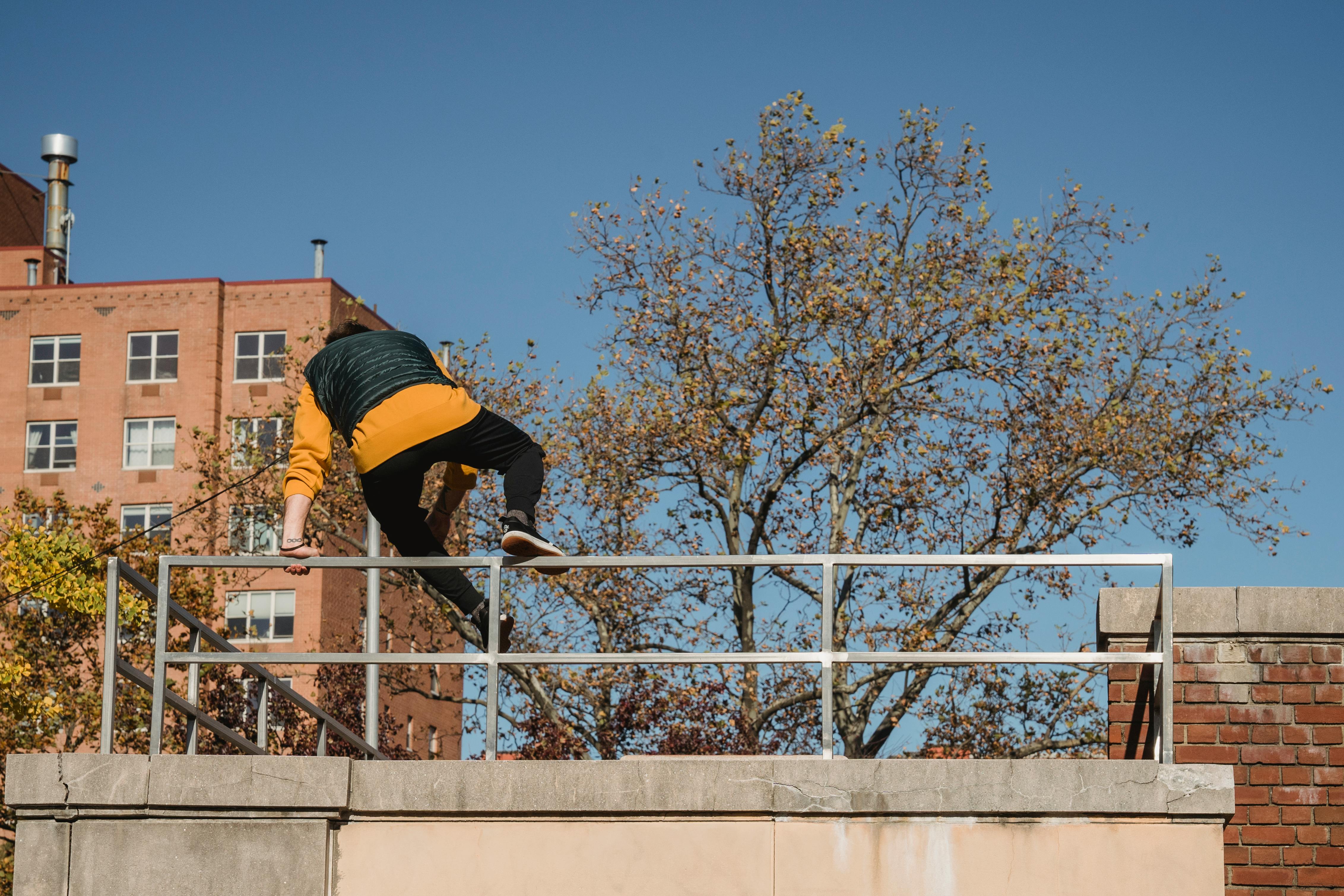 anonymous man jumping over metal fence