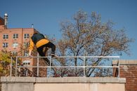 Back view of faceless male in activewear performing trick while practicing on height