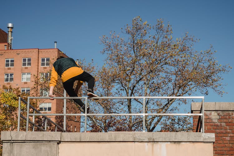 Anonymous Man Jumping Over Metal Fence