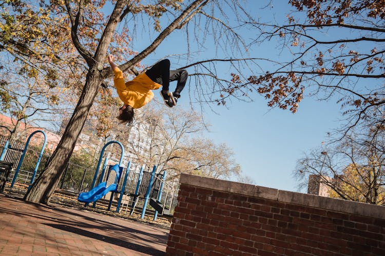 Unrecognizable Man Doing Backflip Trick In Park