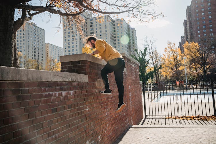 Man Jumping On Fence In City Park