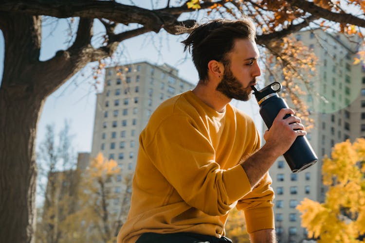 Young Man Sipping Water From Bottle In Park