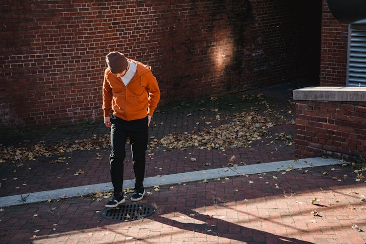 Faceless Man Standing On Street Near At Road Drain