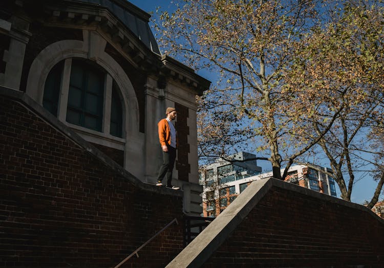 Fit Calm Man Standing On Brick Building Parapet