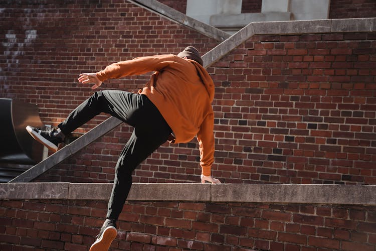 Unrecognizable Man Jumping Over Brick Barrier