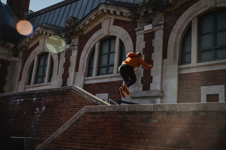 Unrecognizable Person Jumping Over Brick Building Parapet