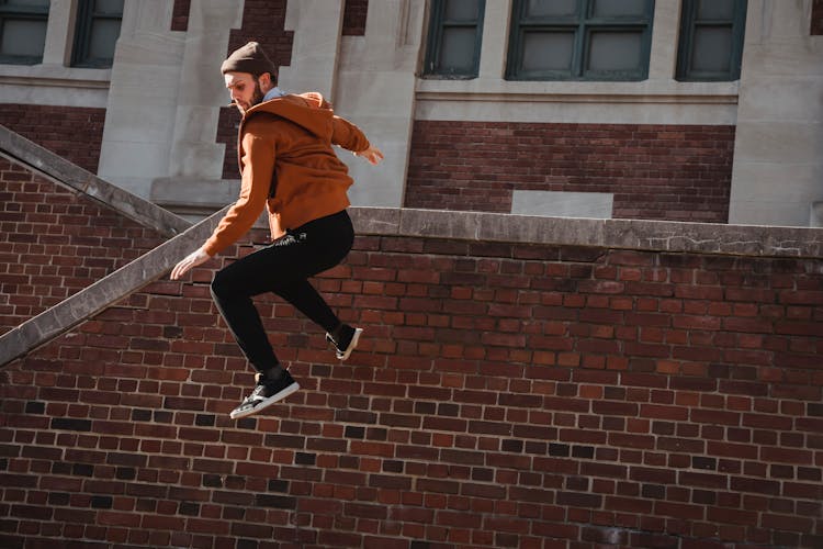 Fit Man Jumping From Brick Parapet