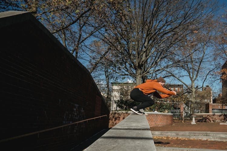 Fit Man Preparing To Jump From Brick Wall