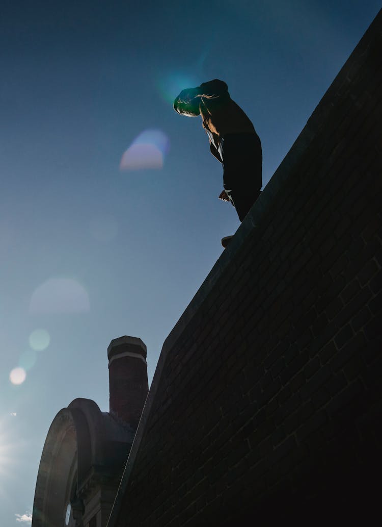 Man Silhouette On Tall Brick Wall