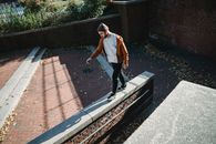 Young man walking on brick barrier top