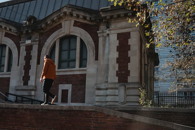 Unrecognizable Fit Man Walking On Brick Building Parapet