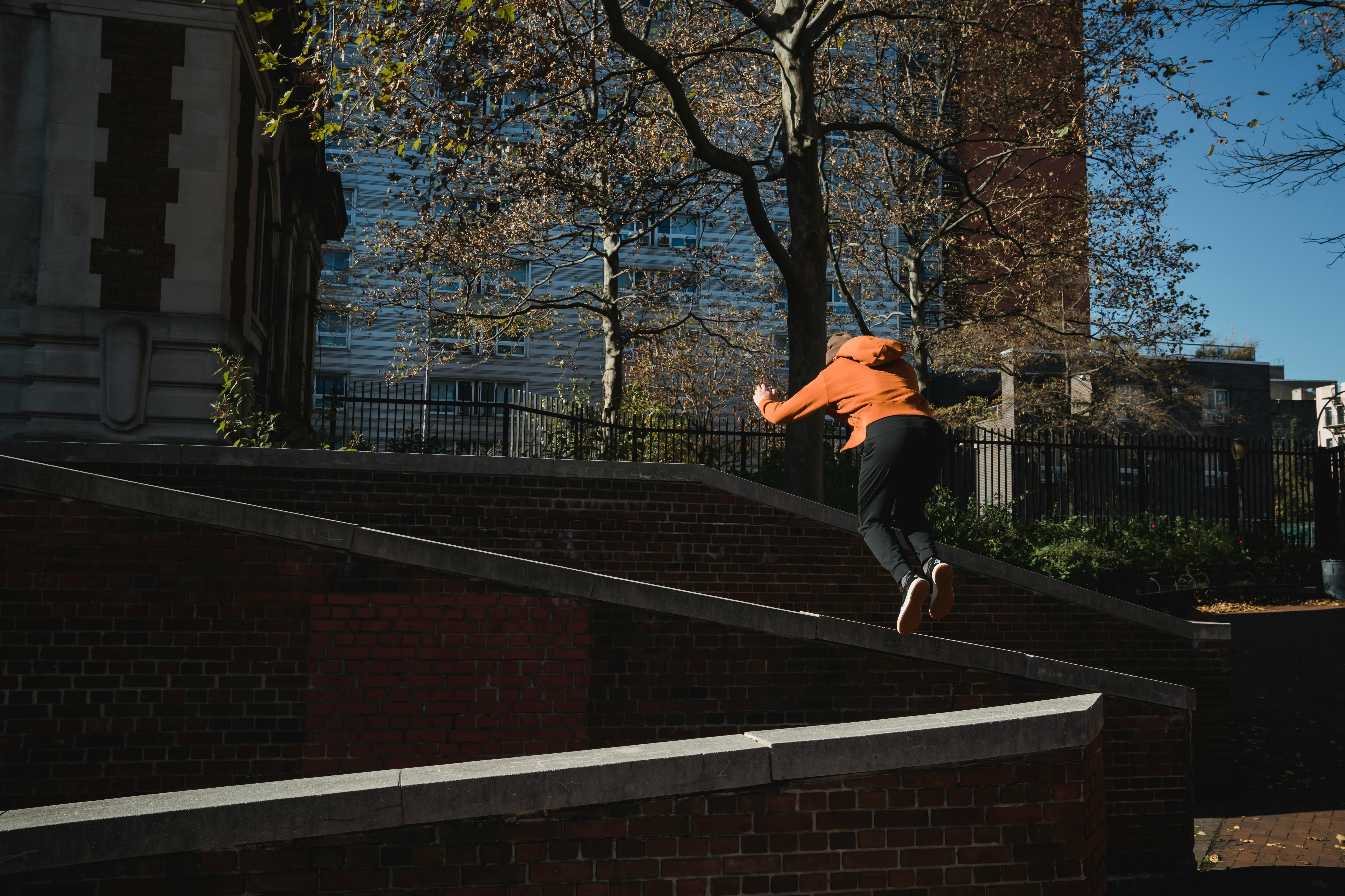 unrecognizable man jumping from brick barrier in city park