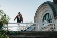 Young man jumping over railing on building roof