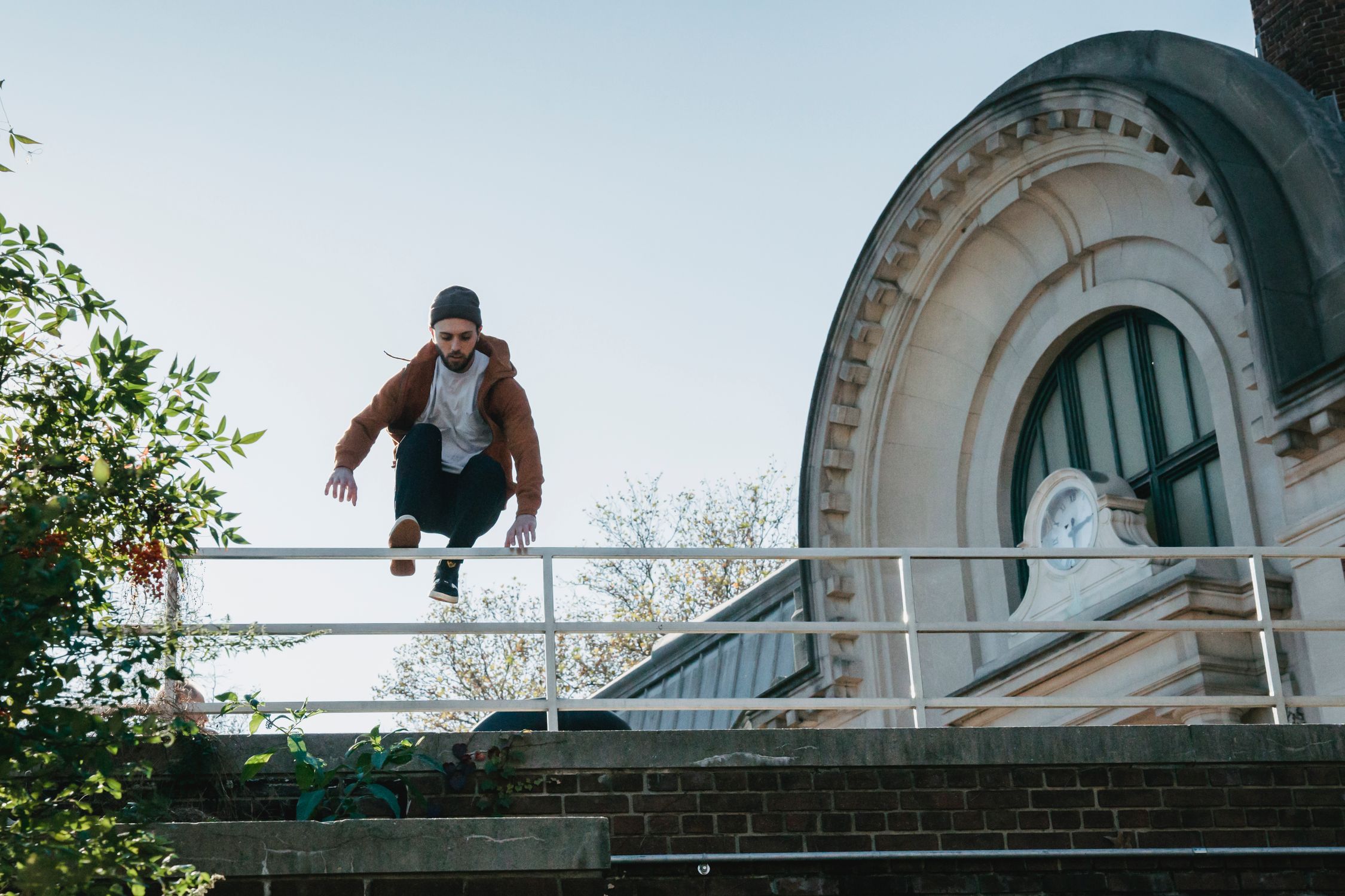 Young man jumping over railing on building roof · Free Stock Photo