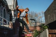 Sporty man jumping from brick building railing