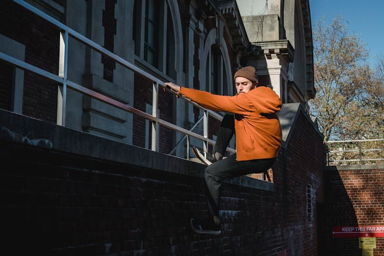 Strong Man Crawling Down On Brick Wall