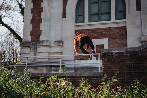 Low angle back view of anonymous male doing leap while training parkour on city street