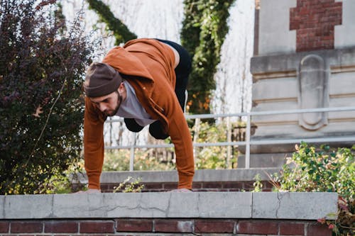 Serious male athlete standing on arms upside down while doing parkour in urban environment