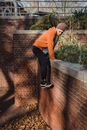 Side view full body of bearded determined male climbing on wall while doing parkour in urban area