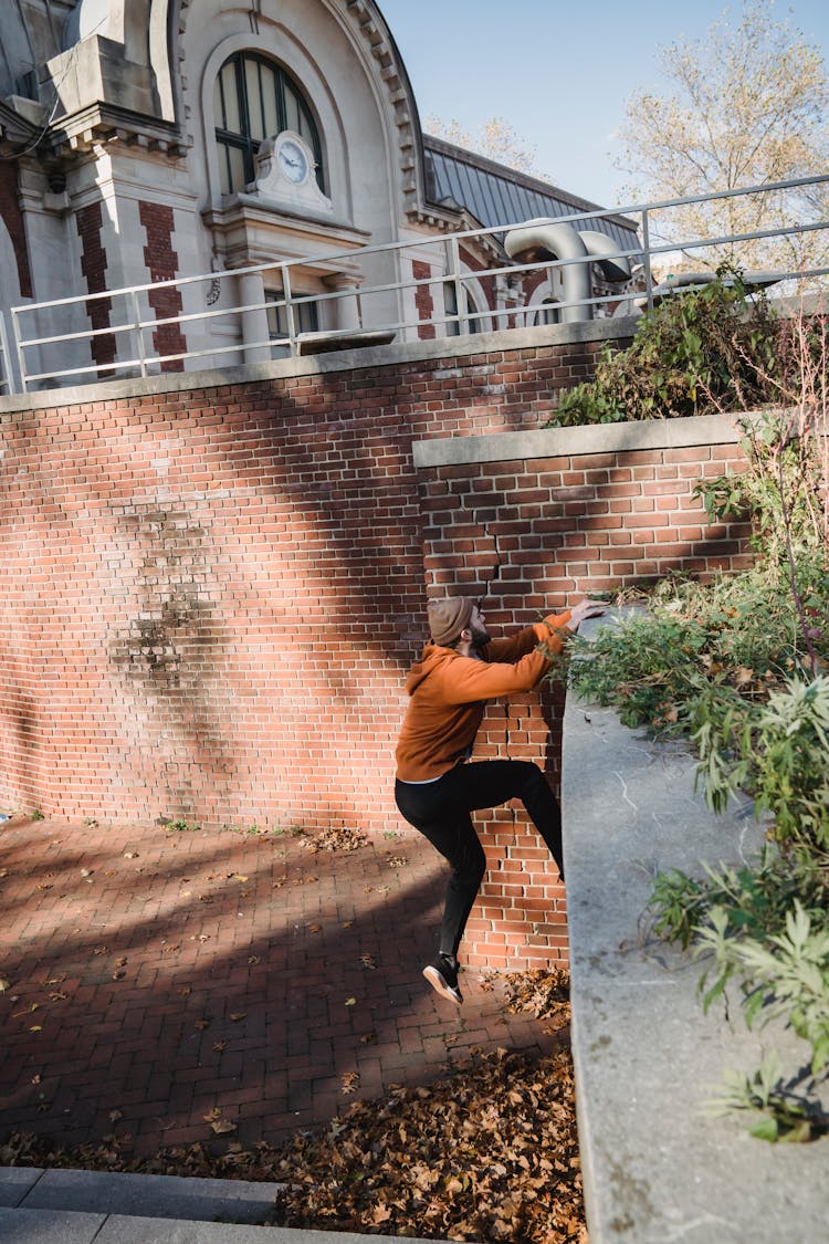 Young Man Climbing On Wall For Parkour Training