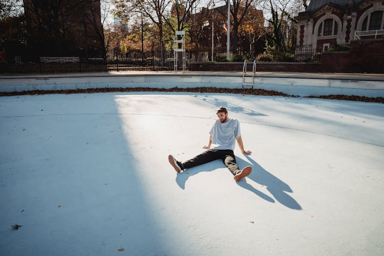 Man Sitting On Bottom Of Empty Pool