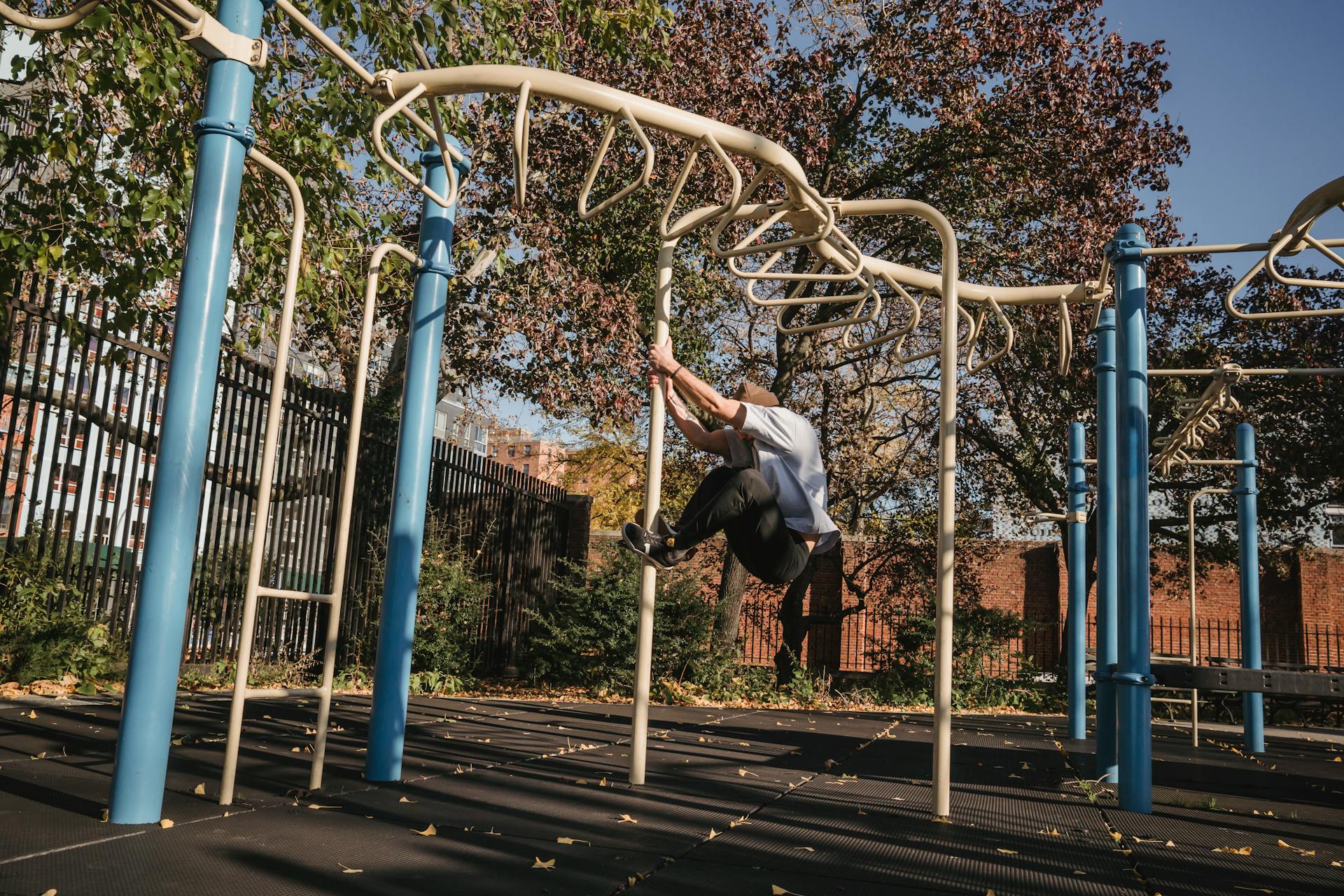 Unrecognizable guy hanging on pole in sports ground