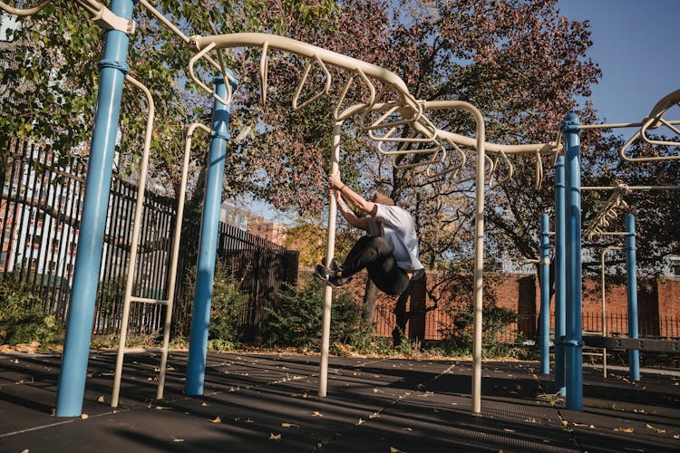 Unrecognizable Guy Hanging On Pole In Sports Ground