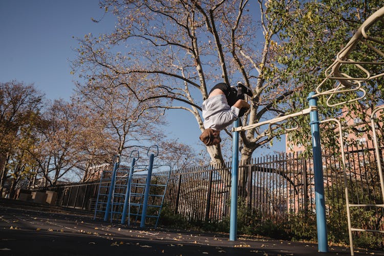 Anonymous Man Doing Backflip In Sports Ground While Parkour