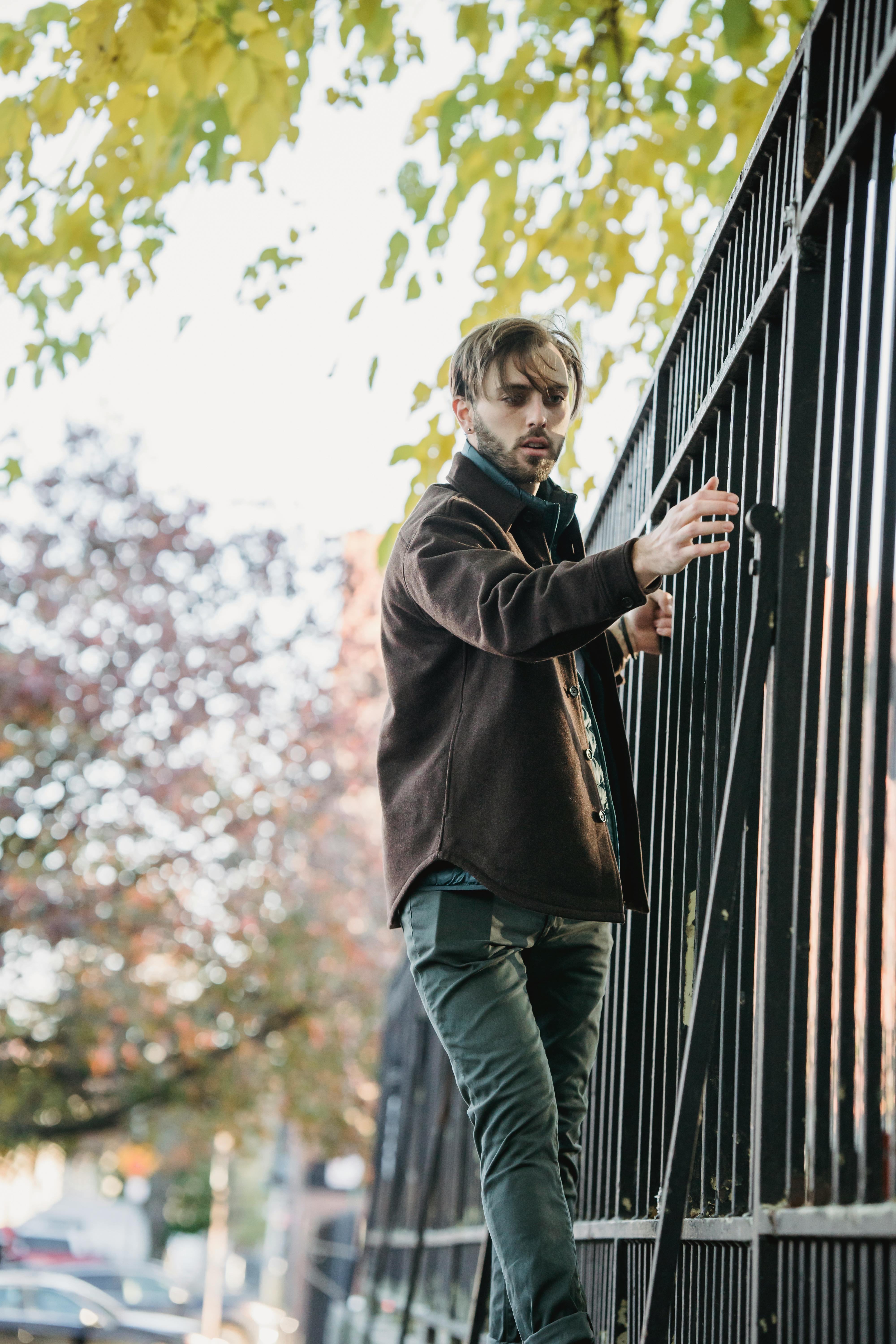 stylish young man holding to metal fence