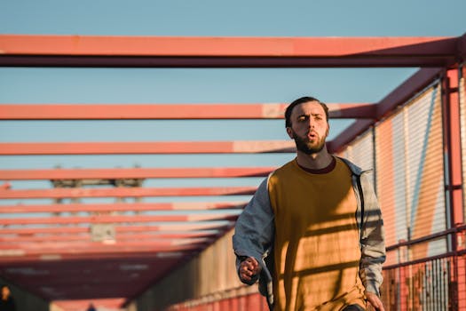 A man jogging on a bridge under clear blue sky, emphasizing fitness and urban lifestyle.
