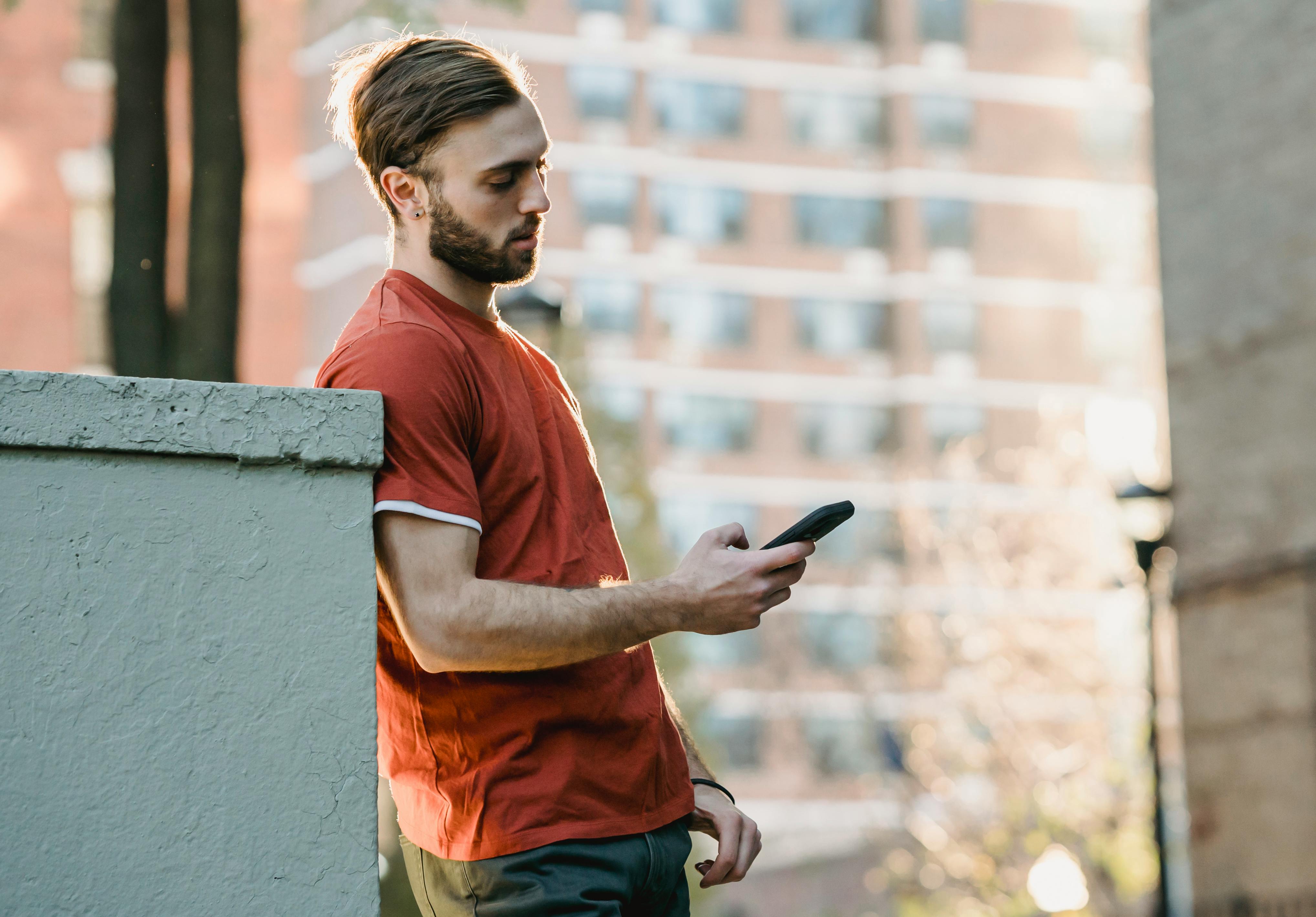 focused bearded man watching smartphone in town