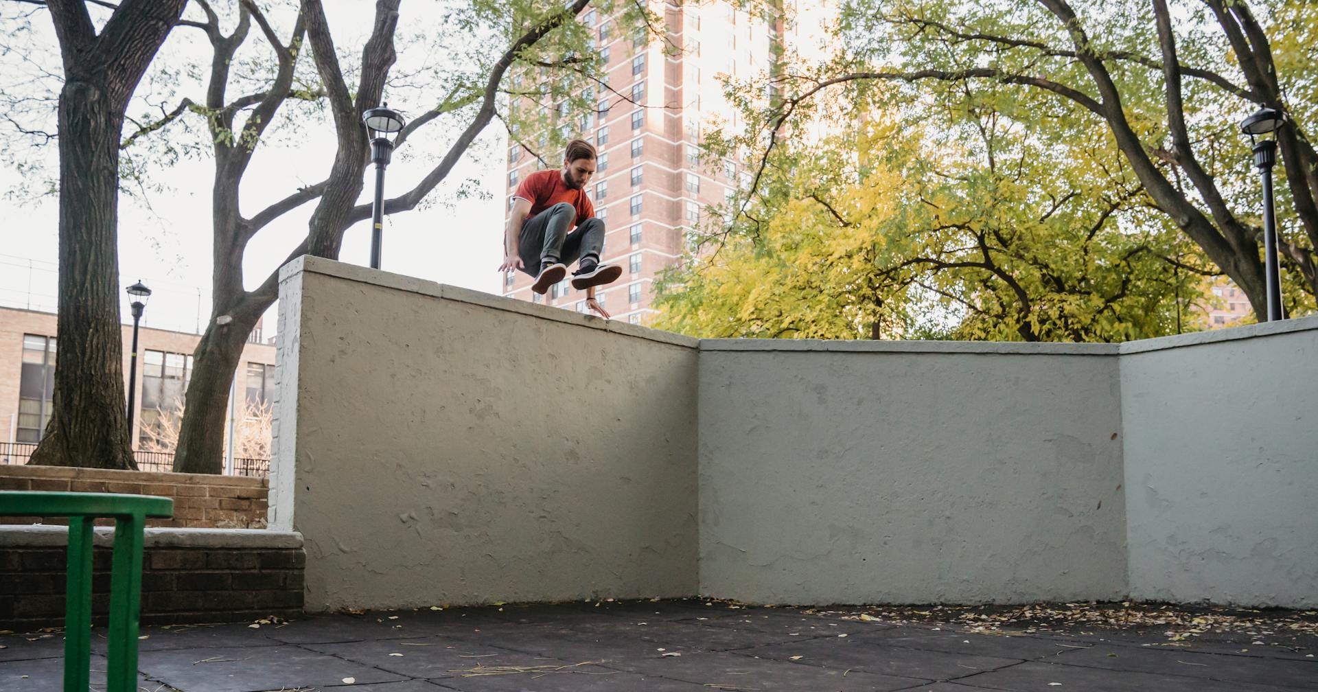 Agile male athlete jumping over obstacle while practicing parkour in town on summer day