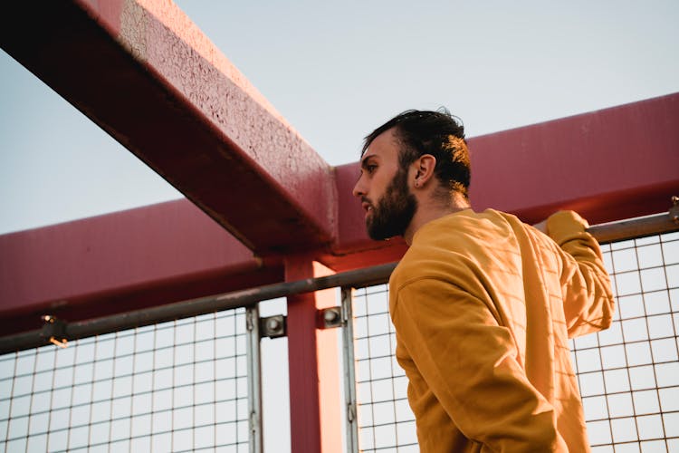 Hipster Man Near Grid Fence On Bridge