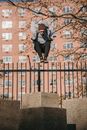 Sporty man jumping on concrete pillar