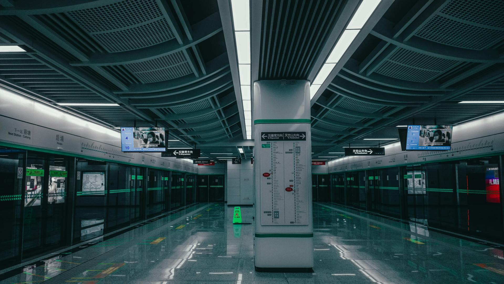 Empty modern subway platform with sleek design and digital signage at night.