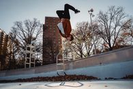 Sportsman performing back flip against city park