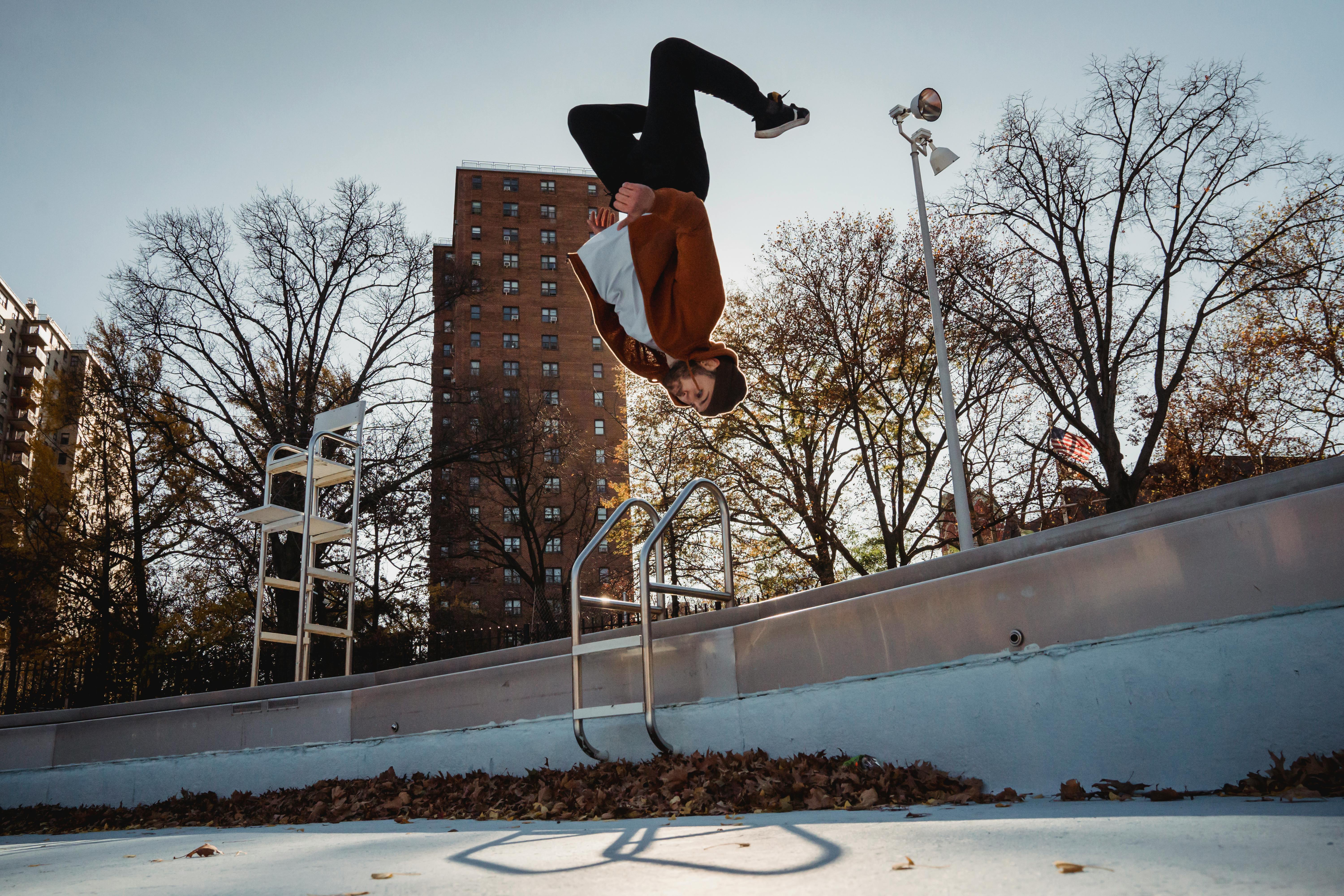 Sportsman performing back flip against city park \u00b7 Free Stock Photo