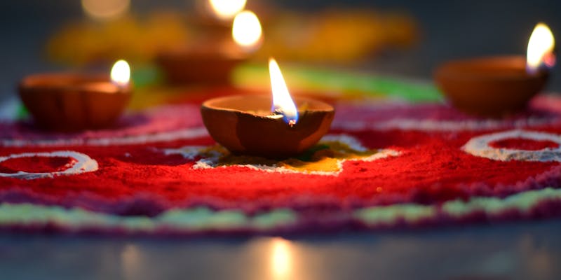 Lit diyas on colorful rangoli for Diwali Lakshmi Puja
