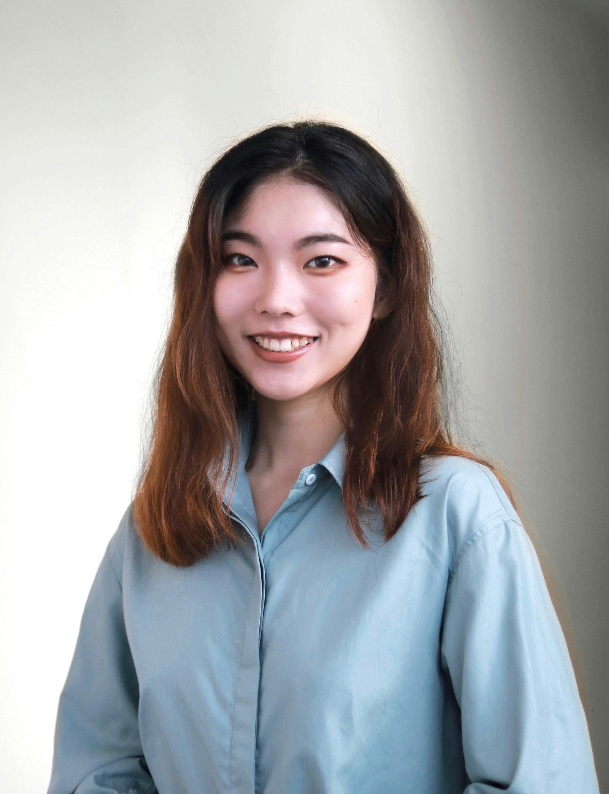 Charming portrait of a smiling woman in a long-sleeve blue shirt against a soft background.