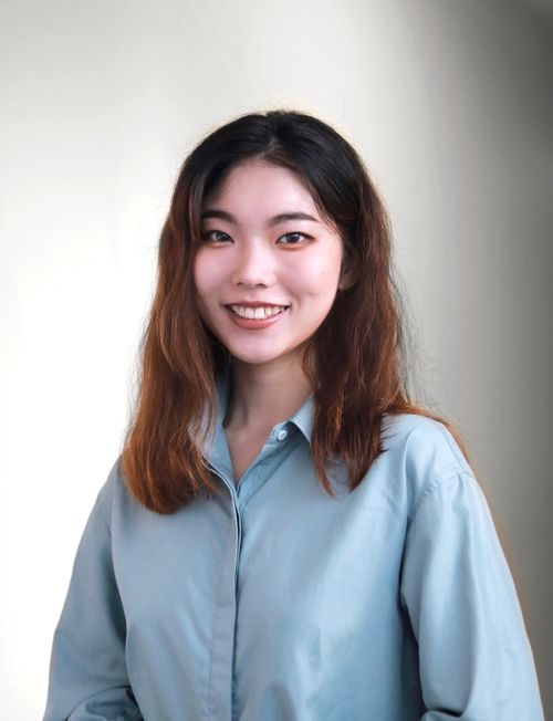 Free Charming portrait of a smiling woman in a long-sleeve blue shirt against a soft background. Stock Photo