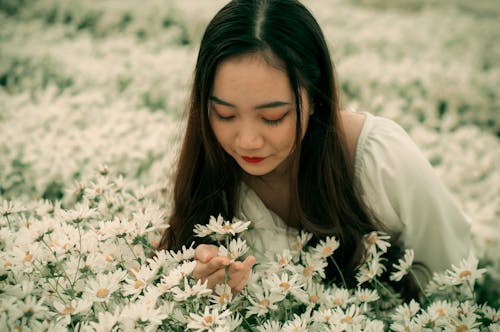 Close-Up Shot of a Pretty Woman Smelling White Daisies