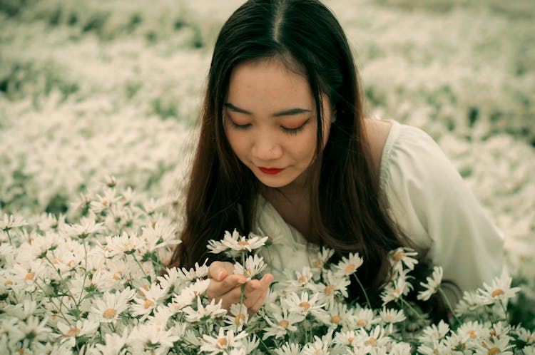 Close-Up Shot Of A Pretty Woman Smelling White Daisies