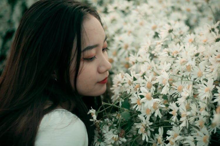 Close-Up Shot Of A Pretty Woman Smelling White Daisies